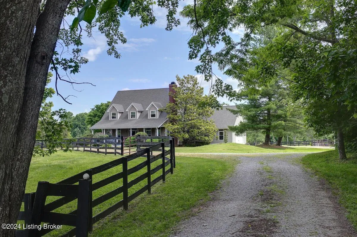 Rural home with potential hail damage on roof accessed by long gravel driveway with wooden fence